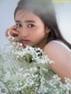 A young woman holding a bunch of white flowers.