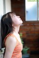 A woman in an orange dress looking up at the sky.