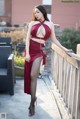 A woman in a red dress standing on a balcony.