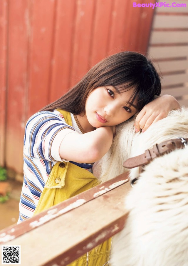 A young woman leaning on a white horse.