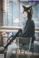 A woman sitting on a chair holding a gun.