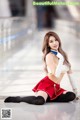 A woman in a red and white outfit sitting on the ground.