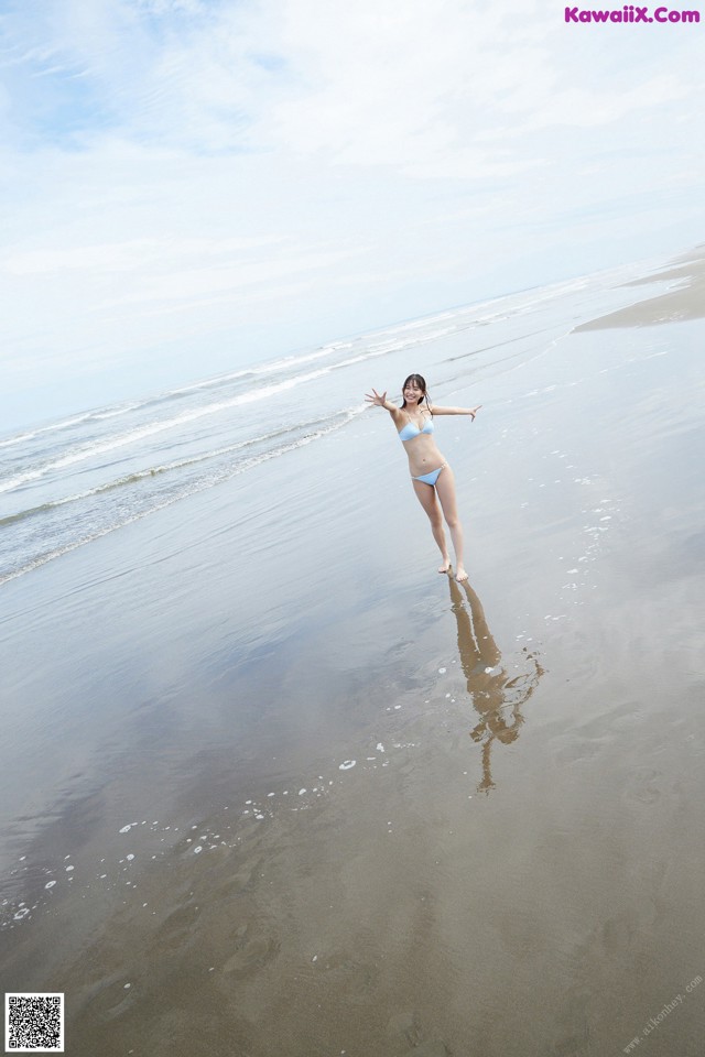 A woman in a blue bikini standing on a beach.