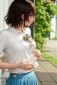 A woman in a white shirt and blue skirt standing on a sidewalk.